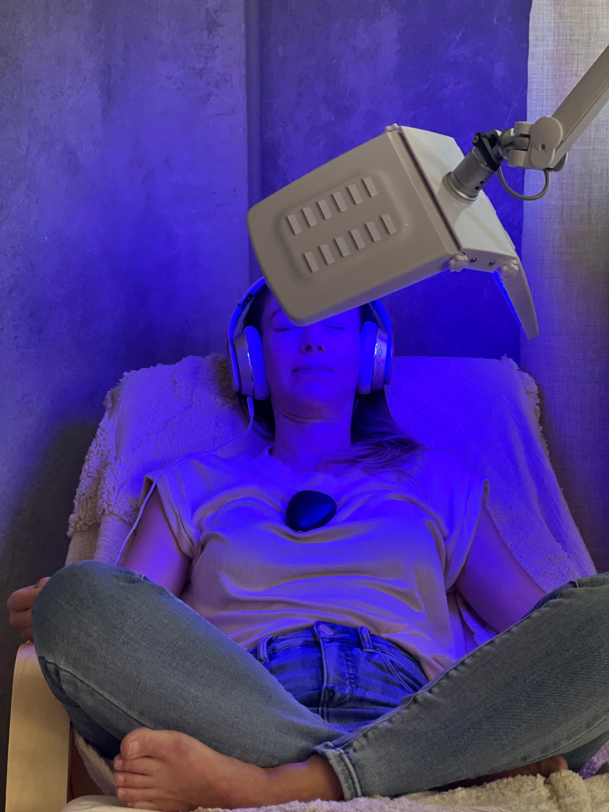 Person sits on chair with LED light and sensate on her chest with headphones on