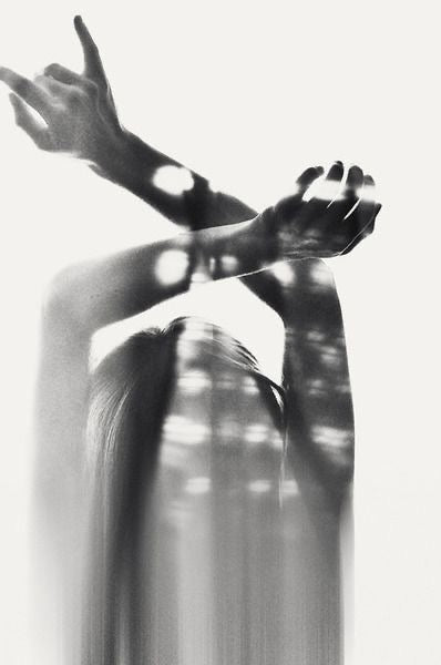 filtered sunlight and shandows of a woman with her arms crossed in the air